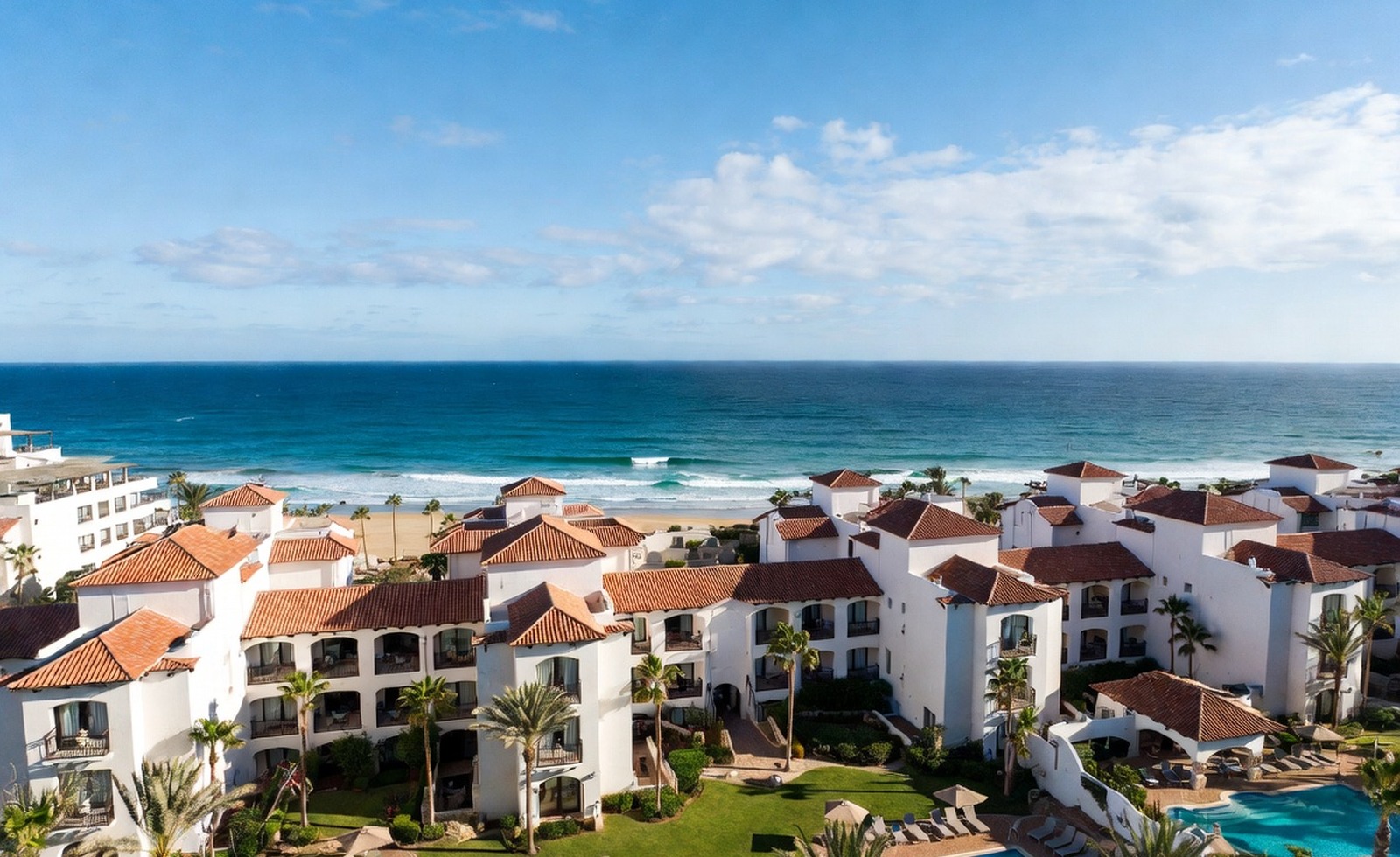 A seaside resort aerial with tiled rooftops and bright ocean water.