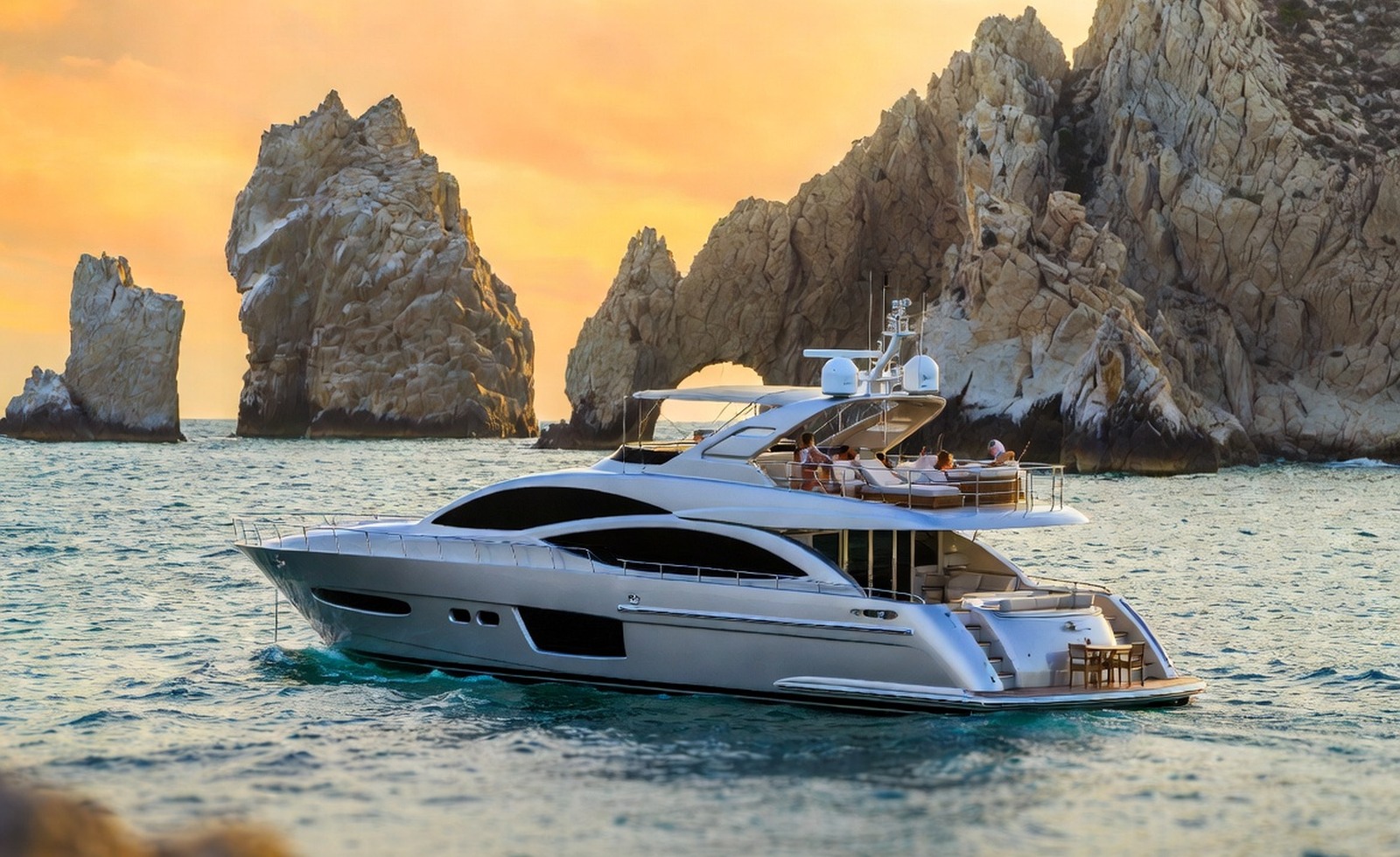A yacht cruising near coastal arches at sunset.